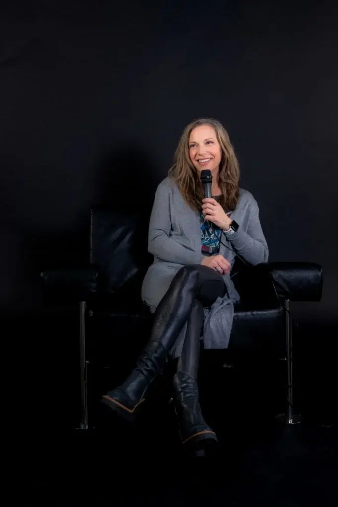 Beth sitting in chair talking in microphone